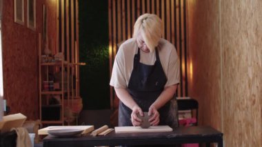 Kısa saçlı, kilden bir parça yoğuran yaşlı bir kadın.