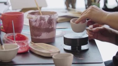 Yaşlı bir kadının elleri döner çarkın üzerine kilden bir bardak koyar.