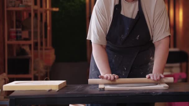 A woman flattening a piece of clay with rolling pin — Vídeo de stock