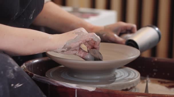 Uppvärmning av lerplattan på keramikhjulet med hjälp av en hårtork och tar bort överflödig lera från insidan — Stockvideo
