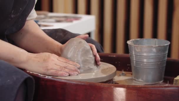 Руки пожилой женщины, мочащей глину на гончарном круге — стоковое видео