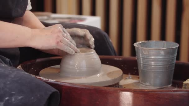 Handen van oudere vrouw begint de vormgeving van een stuk natte klei op het aardewerk wiel — Stockvideo
