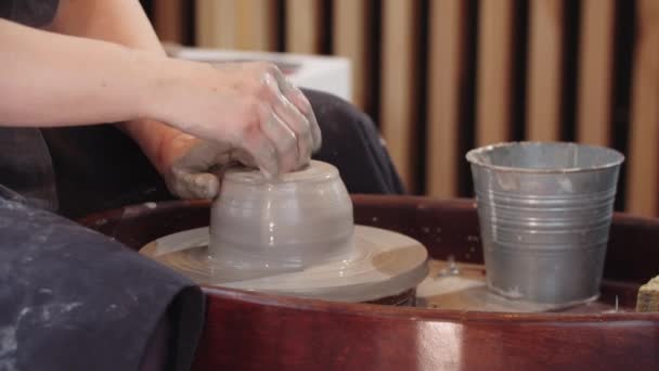 Händer äldre kvinna gör ett hål i bit våt lera och svingar den på keramik hjulet — Stockvideo