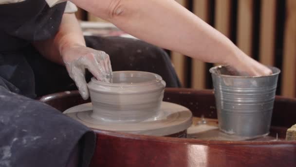 Руки пожилой женщины, вдыхающей дыру в куске мокрой глины на гончарном круге — стоковое видео