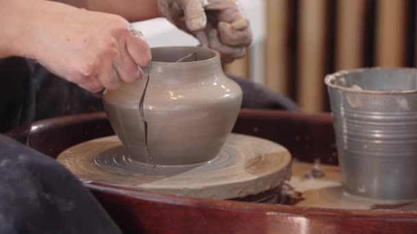 Keramik - en äldre kvinna skär våt lerkruka i två halvor och omformar den — Stockvideo