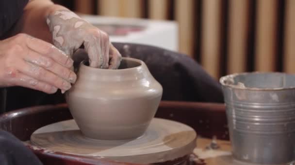 Μια ηλικιωμένη γυναίκα που σχηματίζει πήλινο δοχείο σε κινούμενο κεραμικό τροχό — Αρχείο Βίντεο
