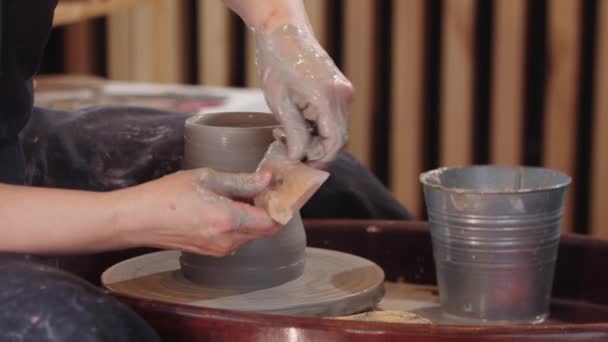 En äldre kvinna formar en hög lerkruka på rörlig keramik hjul — Stockvideo