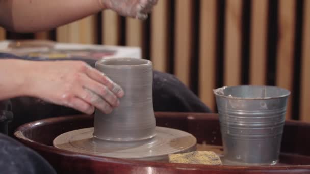 Handen van oudere vrouw vormen een hoge klei pot op bewegend aardewerk wiel — Stockvideo