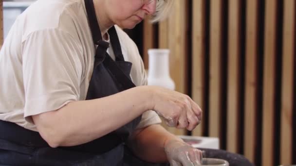 Egy idős nő alakítja a magas agyag edény mozgó fazekas kerék szivaccsal — Stock videók