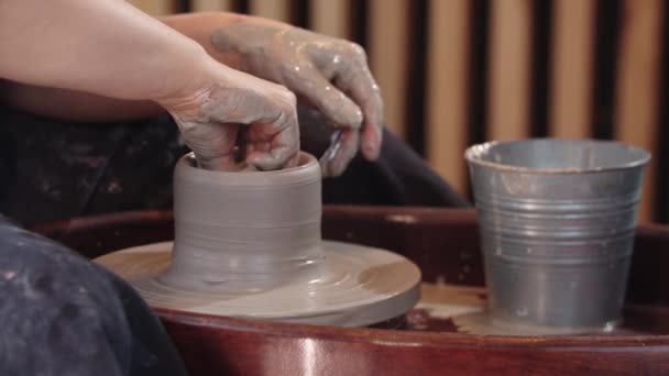 En äldre kvinna formar en hög lerkruka på rörlig keramik hjul - med hjälp av en svamp på insidan — Stockvideo