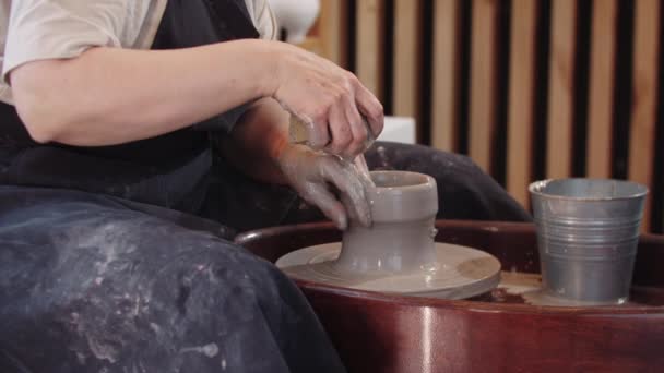 An elderly woman shaping a high clay pot on pottery wheel — Vídeo de Stock