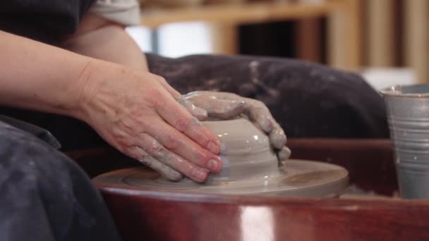 Handen van een oudere vrouw die een gat maakt in het stuk klei — Stockvideo