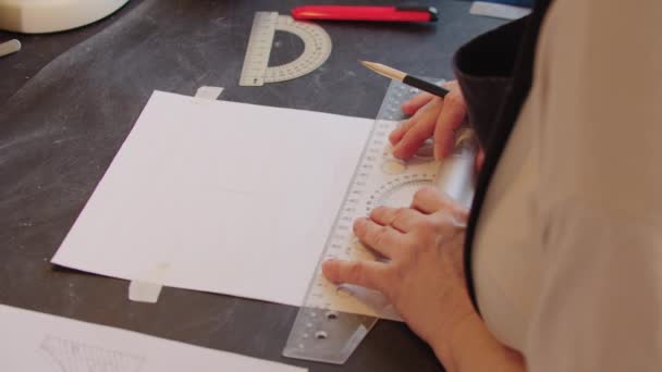 Eine alte Designerin skizziert mit Bleistift und Lineal auf dem Papier — Stockvideo