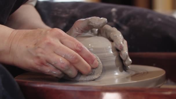Кераміка - формування вологого шматка глини на керамічному колесі за допомогою рук і губки — стокове відео