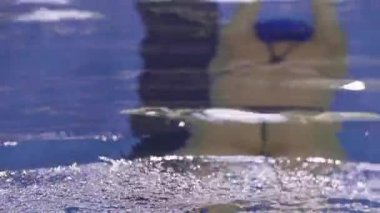 Genç bir kadın yüzücü havuzda yüzer.