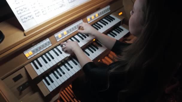 Young woman playing electronic organ by notes — Vídeo de stock