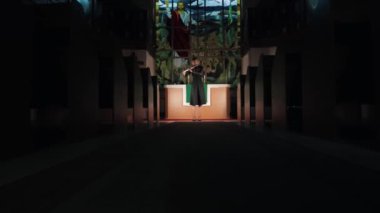 Female flutist playing in church on the background of Christian stained glass windows