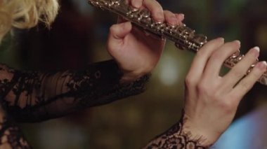 A woman playing flute on a background of stained glass windows