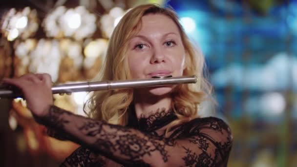 Blonde woman playing flute and looks in the camera — Vídeos de Stock