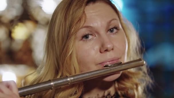 Блондинка играет на флейте на ярком фоне — стоковое видео