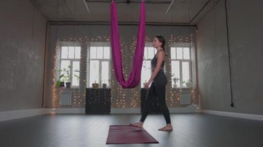 Hava yogası. Genç bir kadın hamağa yürür ve gülümser.