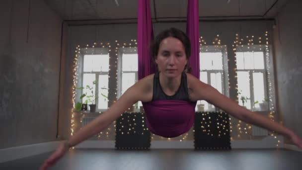 Повітряна йога - молода жінка робить повітряну йогу з нахилом її тіла на гамак — стокове відео