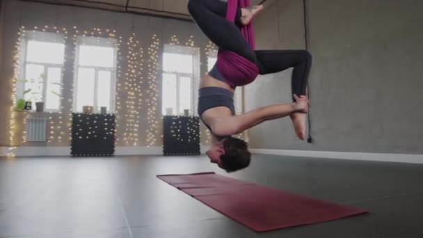 Yoga aéreo - uma jovem mulher gira em uma rede suspensa do teto — Vídeo de Stock