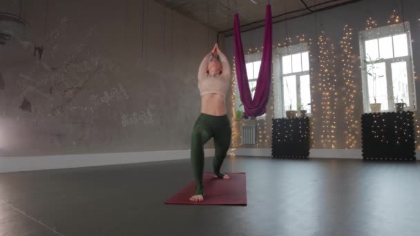 Yoga indoors - a blonde woman doing aerobics in empty studio — Stockvideo