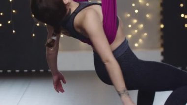 Sırtı yoga hamağında sallanan genç bir kadın.