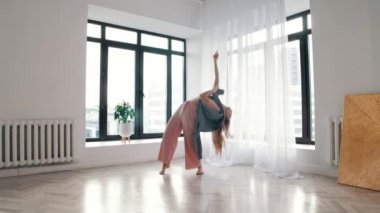 Sokak dansı. Beyaz bir odada plastikçe dans eden genç bir kadın.