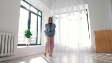 Sokak dansı - mavi kazaklı genç kadın geniş odada dans ediyor