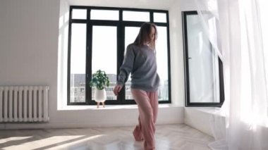 Sokak dansı - mavi kazaklı genç bir kadın pencere kenarında dans ediyor.