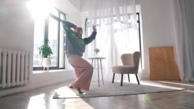 Modern dancing - a young woman with beautiful long hair dancing in a spacious apartment