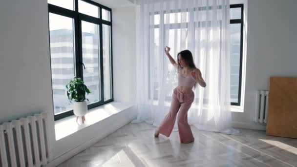 Вуличні танці - молода струнка жінка танцює в білій студії — стокове відео