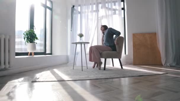 Modern dancing - a young woman dancing near a chair in a spacious room — Αρχείο Βίντεο