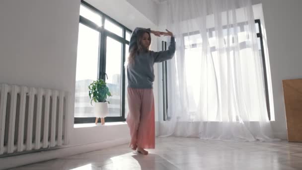 Modern dancing - a young woman with long hair dancing around the spacious empty apartment — Wideo stockowe