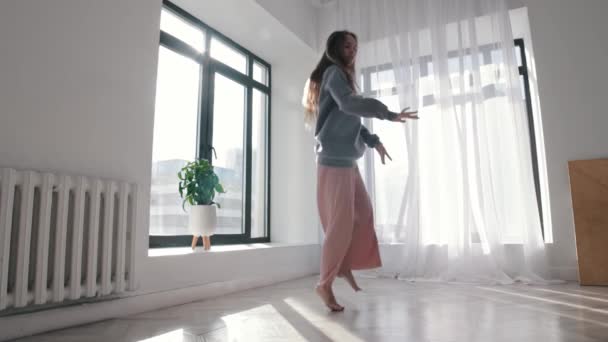 Modern dansen - een jonge vrouw dansend in het ruime lege appartement — Stockvideo