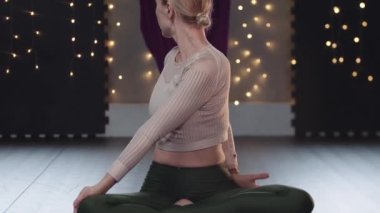 Bir kadın yoga minderinde oturur ve aerobik yapar.