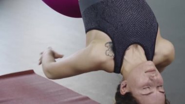 Yoga hamağında sallanan dövmeli genç bir kadın.