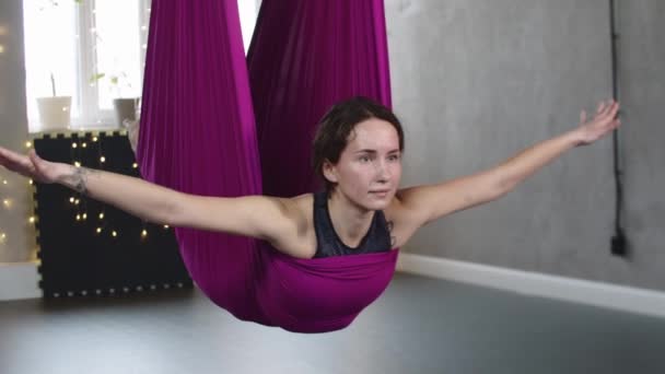 Jovem mulher pendurada na rede de ioga roxa — Vídeo de Stock