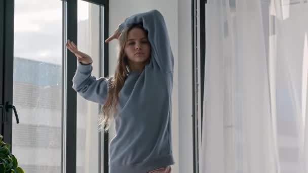 Joven mujer bonita en ropa pastel sintiendo la música por la ventana — Vídeo de stock