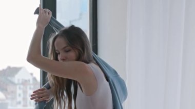 Elinde mavi süveterle dans eden genç bir kadın