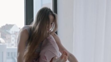 Genç bir kadın dans ediyor ve dansında mavi kazak giyiyor.