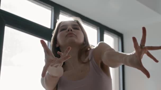 Młoda inspirowana kobieta tańczy przy oknie w jasnym świetle dnia — Wideo stockowe