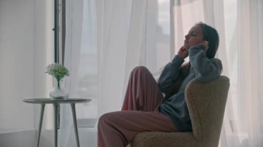 Genç ve ilham verici kadın kablosuz kulaklık takıyor ve yavaşça ayağa kalkıyor.