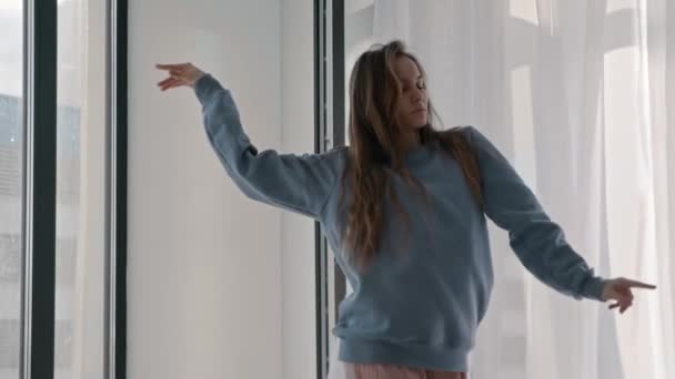 Jovem mulher inspirada em danças de roupas pastel pela janela — Vídeo de Stock