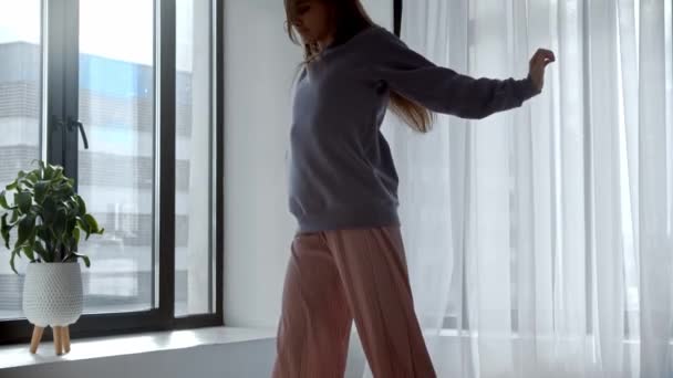 Молода жінка в бездротових навушниках танцює в кімнаті — стокове відео