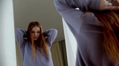 Genç, güzel, uzun saçlı, aynanın önünde dans eden kadın.