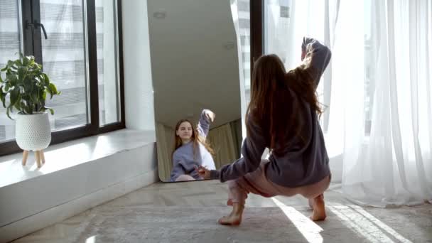 Fiatal csinos nő feláll a tükör előtt és elkezd táncolni. — Stock videók