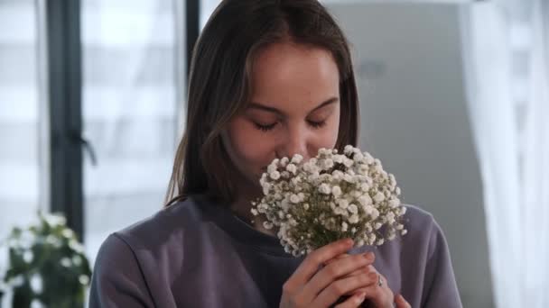 若い女性は小さな白い花を保持し、嗅ぎます — ストック動画